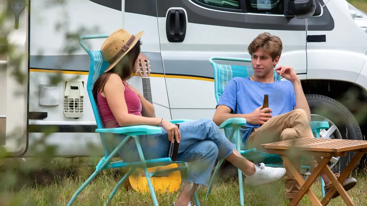 Two campers relaxing in folding chairs beside their RV