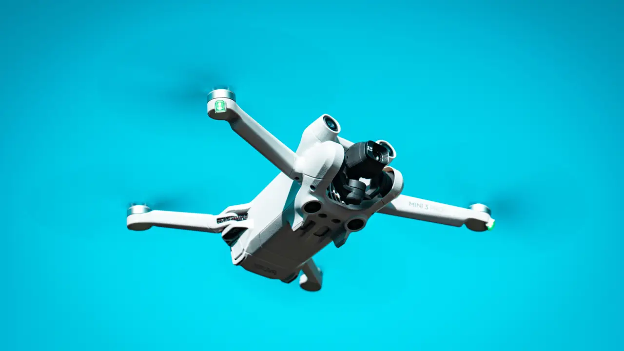 A small camera drone hovering against a blue sky