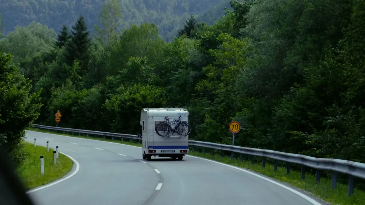 An RV driving a winding road through forested mountains